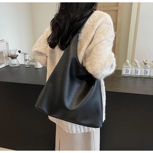 Close-up of black lychee grain leather hobo bag showing the texture and wide shoulder strap
