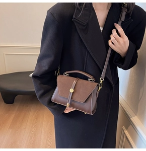 Detail of dark brown suede and leather handbag with gold metal hardware and strap