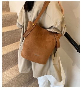 Gros plan du sac seau en daim caramel montrant la texture mate et les détails de la bandoulière