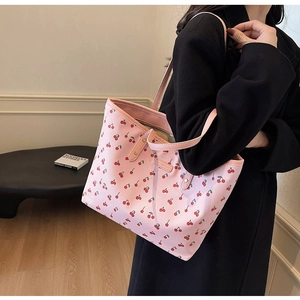 Sac fourre-tout rose à motifs cerises porté sur un manteau d'automne noir élégant