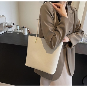 Detailed view of the off-white PU leather tote bag showing litchi texture and shoulder strap