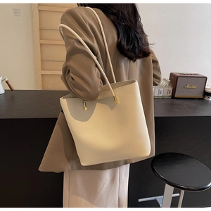 Detail of minimalist cream leather tote bag with lychee texture and gold metal hardware