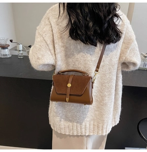 Close-up of retro brown patchwork suede handbag worn by a model in a cafe setting