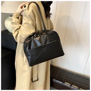 Detail of minimalist black PU leather shoulder bag featuring a front pocket and dual zippers