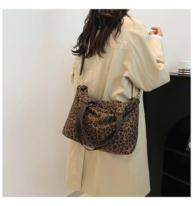 Detail of leopard print canvas tote bag with brown straps and golden metal hardware