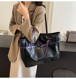 Detail of minimalist black PU leather tote bag with purple straps and metal buckle accents