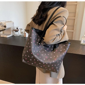 Détail du sac cabas en similicuir noir fleuri avec des nœuds roses et bandoulière