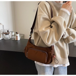 Dettaglio borsa a mezzaluna in nylon marrone scuro con fibbia argento e coulisse rossa laterale