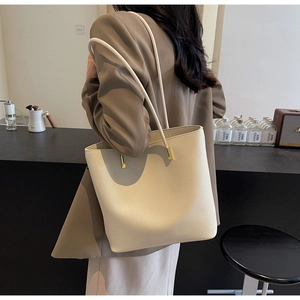 Close-up of cream white tote bag featuring pebble leather texture and gold hardware