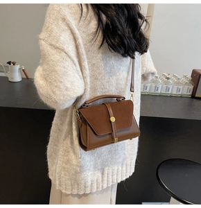 Brown suede crossbody bag with metal buckle shown in a cozy coffee bar setting
