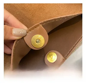 Gros plan d'un sac en cuir PU marron avec un fermoir magnétique doré à texture radiante