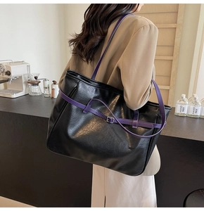 Detail of black PU leather tote bag featuring purple contrast straps and metal buckle accents