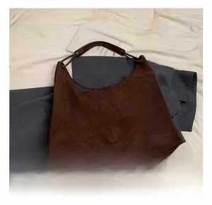 Gros plan sur un sac hobo en daim marron avec texture mate douce et grande capacité