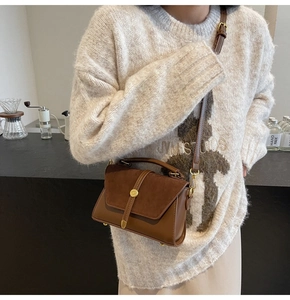 Detailed close-up of suede crossbody bag with golden buckle and sleek stitching