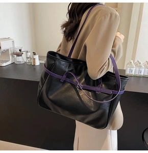 Detail of black PU leather tote bag with contrasting purple straps and metal buckle