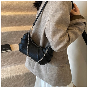 Detail of black pleated PU cloud bag with silver chain strap on a blazer outfit