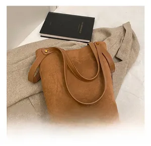 Gros plan détaillé d'un cabas en cuir PU marron mat avec rivets dorés et logo gravé