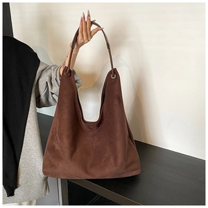 Détail de la texture d'un sac hobo en daim marron foncé avec des œillets vintage