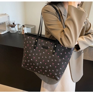 Détail du grand sac cabas fleuri montrant les nœuds roses et la plaque logo métallique
