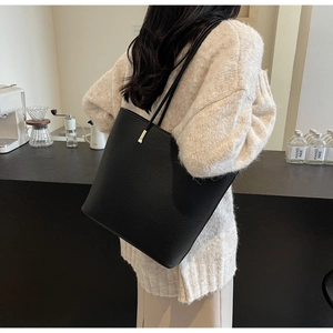 Close-up of black lychee grain PU leather tote bag with elegant gold hardware accents