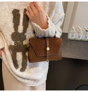 Detail of vintage brown suede shoulder bag featuring a metallic swivel lock and flap closure