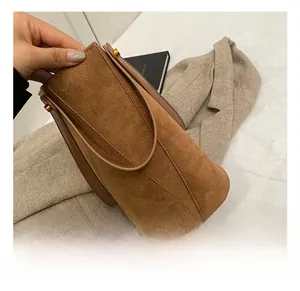 Détail du sac bandoulière en daim marron avec boucle dorée et bandoulière en cuir