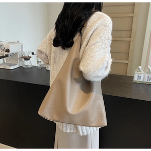 Detail of taupe oversized tote bag with lychee texture shown on a female model