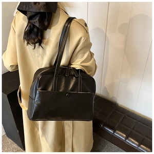 Detail view of black minimalist PU leather tote bag with a front snap pocket and zippers