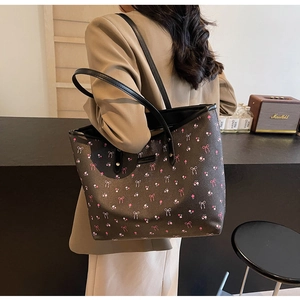 Sac fourre-tout à fleurs roses avec anses en similicuir noir porté par un mannequin
