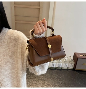 Detail of vintage brown leather and suede handbag with golden metal buckles on the handle