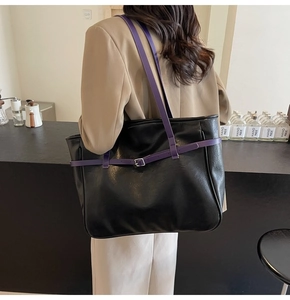 Detail view of large black PU tote bag with purple straps and buckle on shoulder