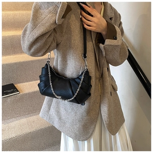 Detail of black pleated PU leather crossbody bag with silver chain and lychee texture finish