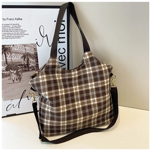 Classic plaid hobo shoulder bag with brown adjustable straps in a minimalist indoor setting
