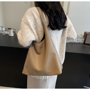 Detail of a large khaki pebbled leather shoulder tote bag shown in a lifestyle setting