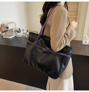 Macro detail of black PU leather tote bag with purple straps and silver metal buckle