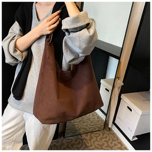Détail d'un grand sac hobo en daim marron montrant sa texture douce et son tombé naturel sur l'épaule