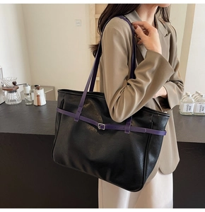 Close-up of black lychee grain leather tote bag with contrasting purple strap and buckle