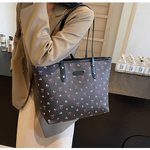 Détail du grand sac cabas avec nœud rose, imprimé fleuri et plaque de marque en métal