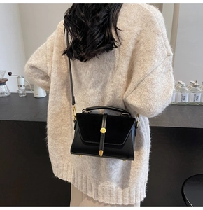 Detail of black suede patchwork handbag with gold round buckle and leather strap