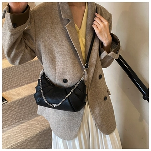 Detail of black crescent crossbody bag featuring pleated PU leather and silver chain strap