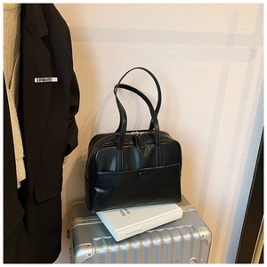 Minimalist black PU leather shoulder bag for women on a silver suitcase for travel