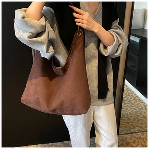 Détail du sac cabas en daim marron avec intérieur spacieux et décor d'oeillets en métal