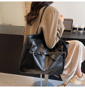 Detail shot of a large black PU leather tote bag with stylish decorative metal buckle