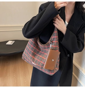 Detail of red and black plaid shoulder bag with detachable brown leather card holder