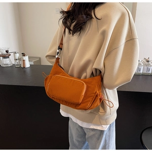 Dettaglio borsa a spalla in tessuto arancione con coulisse e tracolla in pelle marrone
