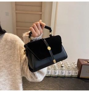 Detail of a black suede leather handbag featuring a vintage gold buckle and handle