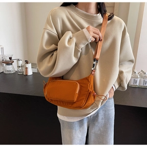 Dettaglio borsa a tracolla arancione in nylon con tracolla regolabile e tasca zip