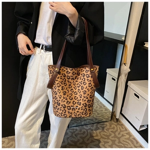Détail du sac fourre-tout à motif léopard avec lanières brunes porté par un mannequin