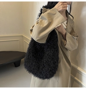 Détail d'un sac cabas en fausse fourrure noire avec texture pelucheuse sur trench beige