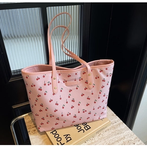 Sac fourre-tout rose avec imprimé cerise rouge et fines bandoulières sur marbre